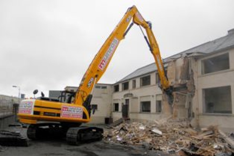 A JCB JS330 HRD excavator purchased by W Munro Construction dismantles the Nicolson Institute in Stornaway as part of the multi-million pound Western Isles Schools Project.