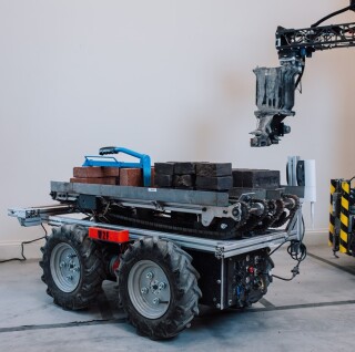 the robots are supplied bricks by electric autonomous ground vehicles