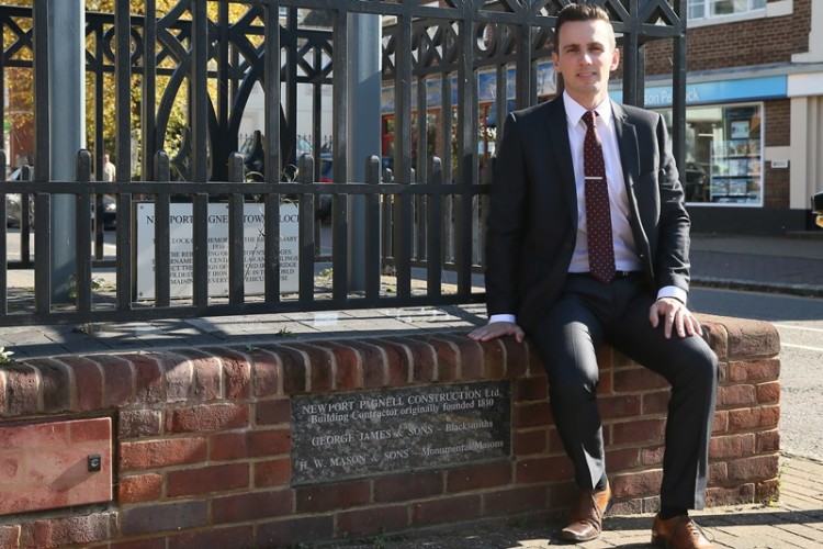 Simon Haddy sitting at the Newport Pagnell Town Clock, which Newport Pagnell Construction helped build.