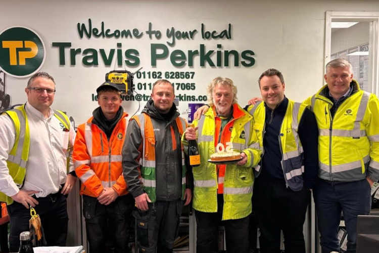 Mick Ballard (holding the champagne and cake) celebrates his 50th anniversary at Travis Perkins with workmates