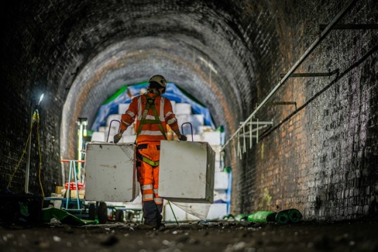 An Amey operative carries a pair of EPS blocks down the tunnel