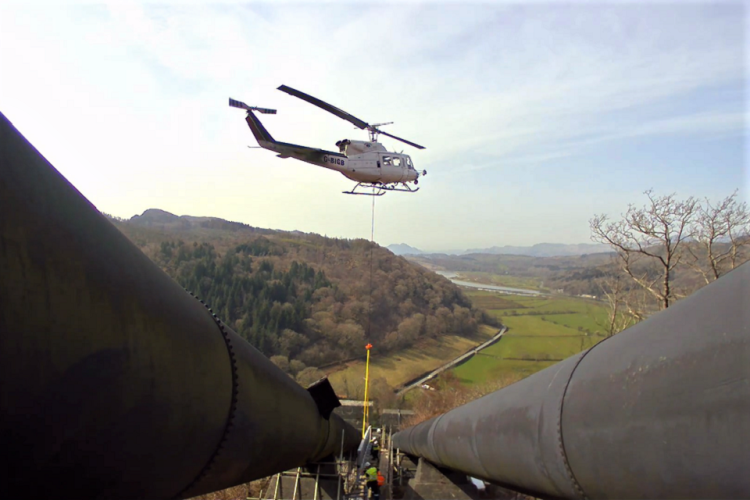 The helicopter pilot lifted the bridge beams into position between the pipelines