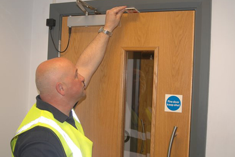 A FDIS inspector checks a fire door