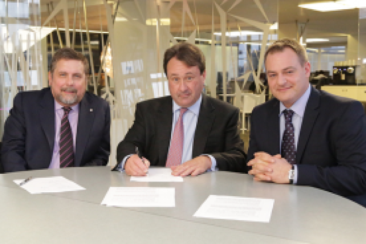 John Morgan (centre) signs the agreement