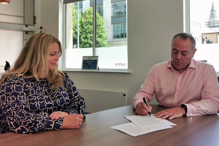 Curtins chief executive Rob Melling (right) signs over the business, alongside Cardiff office manager Helene John, one of the two elected employee trustee directors