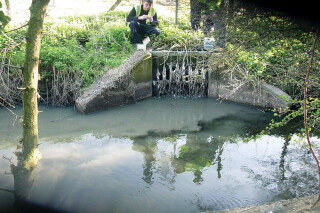 An Environment Agency worker collects water samples from an outflow into the Thames near Didcot