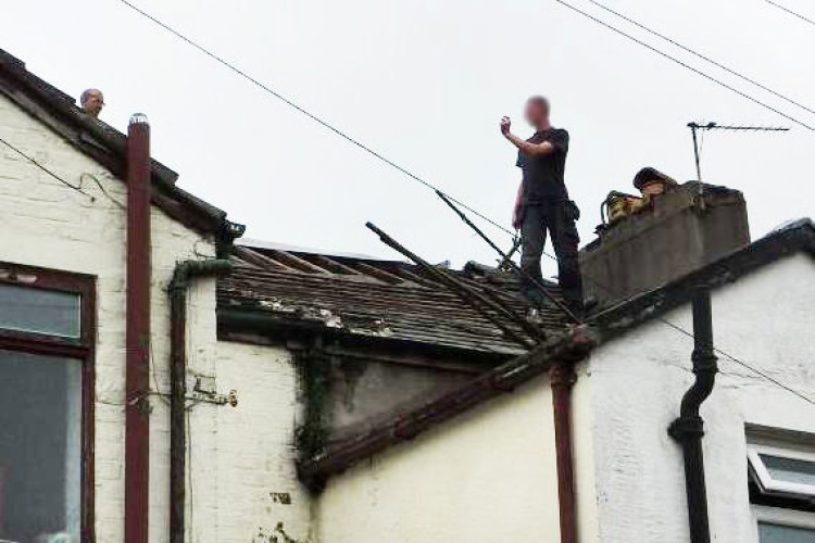 A worker on the roof of the Kearsley Fish Bar where Alex Morrisey put lives at risk